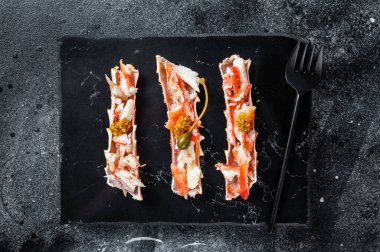 Bitkilerle dolu bir kılıfta yengeç bacağı eti. Siyah arka plan. Üst görünüm