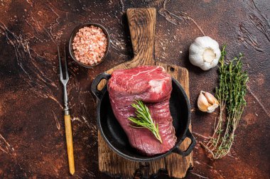 Tavada çiğ sığır fileto eti ve otlar. Karanlık arka plan. Üst görünüm