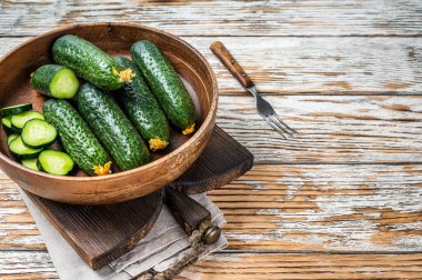 Tahta bir tabakta çiğ organik salatalık. Beyaz tahta arka plan. Üst Manzara. Boşluğu kopyala