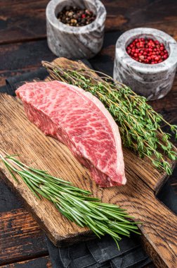 Wagyu A5 çiğ but ya da sığır filetosu, kasap tahtasında kobe eti. Koyu ahşap arka plan. Üst görünüm