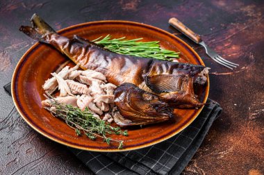 Sıcak füme balık filetosu kekik ile birlikte kırsal bir tabağa konmuş. Karanlık arka plan. Üst görünüm