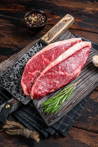 Biftecks de viande de bœuf hachés crus sur une planche de boucher avec un coupe-viande. Fond en woden foncé. Vue du dessus — Photo