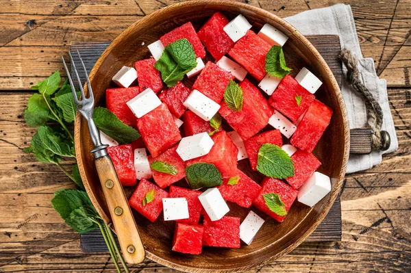 Zomer Watermeloen Salade met feta kaas en munt in een houten bord. Houten achtergrond. Bovenaanzicht — Stockfoto