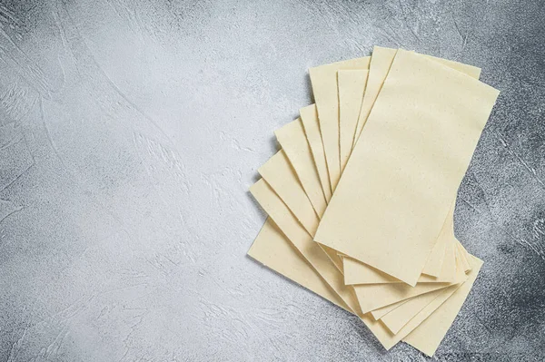 Rohe Lasagneblätter stapeln sich auf einem Küchentisch. Weißer Hintergrund. Ansicht von oben. Kopierraum — Stockfoto