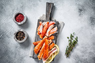 Ahşap bir tahtanın üzerinde otlarla pişirilmiş Kral Yengeç bacağı eti. Beyaz arka plan. Üst görünüm