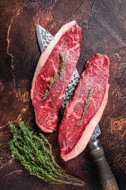 Pişmemiş çiğ sığır filetosu ya da kasap bıçağında biftek. Karanlık arka plan. Üst görünüm