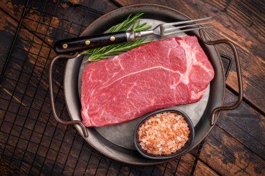 Bitkilerle çiğ biftek pişirmeye hazırım. Ahşap arka plan. en üstteki görünüm.