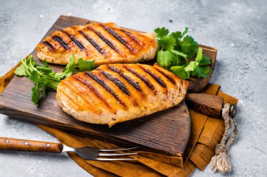 Kesme tahtasında tavuk göğsü bifteği, ızgara tavuk eti, üst manzara, gri arka plan.