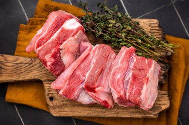 Taze kuzu pirzolası, ahşap tahtada kekik olan koyun eti. Siyah arka plan. en üstteki görünüm.