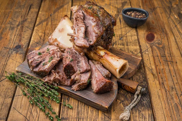 Yavaşça pişirilmiş dana ossobuco ve sulu et parçaları ahşap arka planda kemik iliği otları..