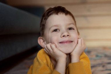 Çocuk gülümseyerek yerde yatıyor.