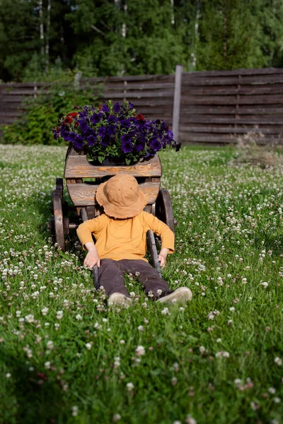 Niño Sombrero Está Sentado Hierba Cerca Carro Decorativo Con Flores —  Fotos de Stock