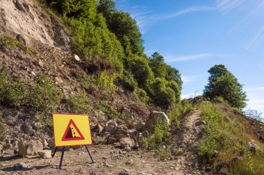 Landslide in forest dirt road and warning sign. clipart