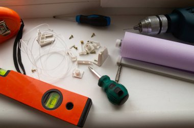 Bir tutacağı olan bir pencere silindiri kurulumu. Kurulum aracı. Tornavidalar, matkaplar, seviye, paten kepenkleri ve bağlayıcılar.