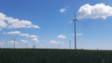 Enerji ve endüstri. Tarlada dönen pervaneleri olan devasa rüzgar türbinleri. Alternatif, yenilenebilir enerji kaynakları.