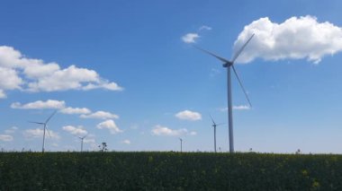 Enerji ve endüstri. Tarlada dönen pervaneleri olan devasa rüzgar türbinleri. Alternatif, yenilenebilir enerji kaynakları.