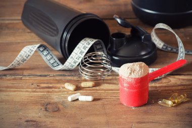 peynir altı suyu protein tozu kaşık vitaminler ve ahşap zemin üzerinde plastik shaker içinde