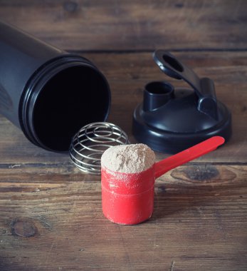 Peynir altı suyu protein tozu kepçe ve ahşap arka plan üzerinde plastik shaker