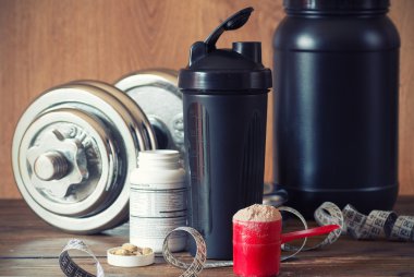 Whey protein powder in scoop with vitamins on plate on wooden background clipart