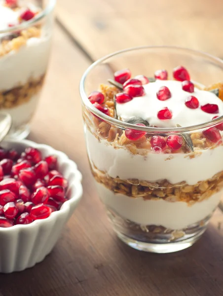 Café da manhã saudável - iogurte com granola caseira e romã na placa de madeira brilhante — Fotografia de Stock