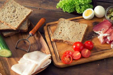 Kahvaltı sandviç dilimlenmiş jambon ve ahşap masa üzerinde domates