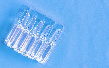 Masanın üzerinde mavi arka planda şeffaf ambalajlar var. Tıbbi cam ampulleri kapatın..