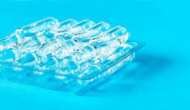 Masanın üzerinde mavi arka planda şeffaf ambalajlar var. Tıbbi cam ampulleri kapatın..