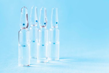 Masanın üzerinde mavi arka planda cam tıbbi ampuller var. Tıbbi cam ampulleri kapatın..