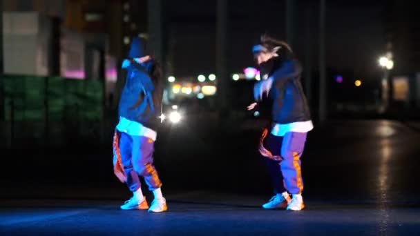 两个精力充沛的年轻女子跳嘻哈舞 夜晚在城市街道上的灯笼里自由自在 — 图库视频影像