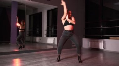 Koreografi stüdyosunda dans eden çağdaş ve şehvetli genç bir kadın aynanın önünde dans ediyor. Yavaş çekim.