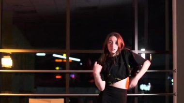Dans stüdyosunda dans eden güzel bir gogo dansçısı. Büyük bir aynanın önünde. Ağır çekim. Orta uzunlukta.