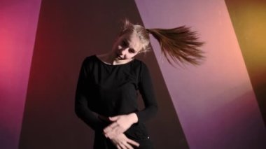 Genç plastik bir kadının koreografi stüdyosunda serbest dans ederken orta boy bir pozu.