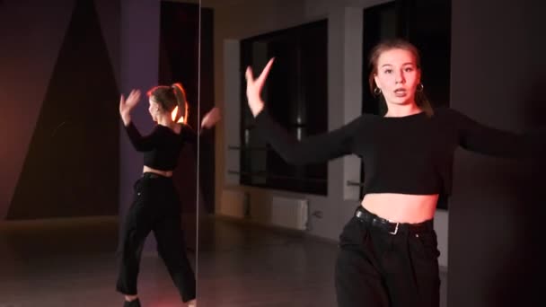 大きな鏡の前のダンススタジオで現代の若い振付を踊る美しい女性のゴゴダンサー — ストック動画