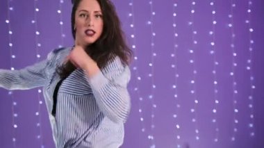 Uzun saçlı şık bir genç kadın, bir koreografi stüdyosunda twerk elementleriyle modern dans ediyor. Yavaş çekim.