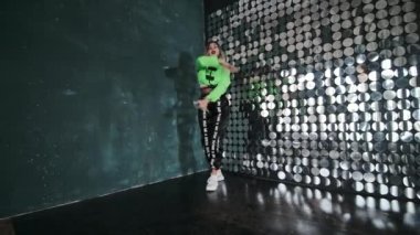 Uzun saçlı, zarif genç bir kadın. Bir koreografi stüdyosunda twerk elementleriyle modern dans ediyor..