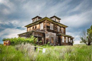 Saskatchewan ovalarında, ön planda beşiği olan terk edilmiş, eski bir ev.