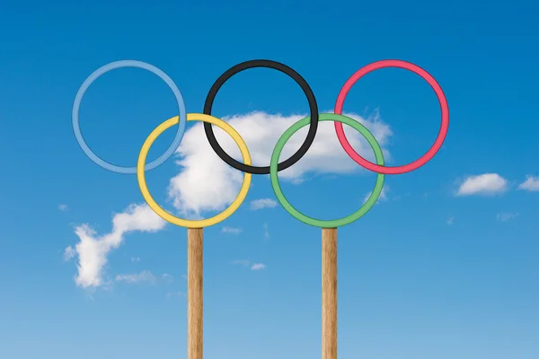 Olympiske ringe står under lyse blå himmel - Stock-foto