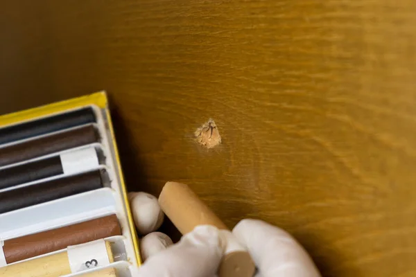 furniture restoration,the master closes the hole in the wooden surface with wax pencils close-up
