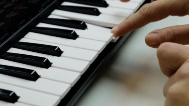 Sentezleyici çalıyor, parmaklar piyano tuşlarında.