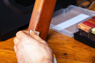 Usta, ahşap mobilya onarım onarımı sırasında bacağındaki bir çiziği siliyor.