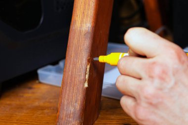 restoration and repair of wooden furniture the master hand closes the scratch with a special marker clipart