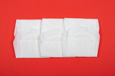 Kırmızı arka planda kadın pedi, kadınlarda adet sembolü.