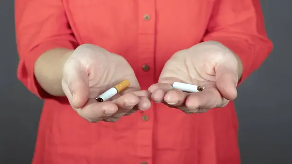 broken cigarette in female hands,stop smoking sign