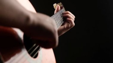 Karanlık bir odada gitar çalıyor. Yakından fretboard akustik gitar çalıyor.