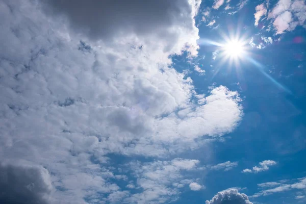 white sun with clouds on blue sky