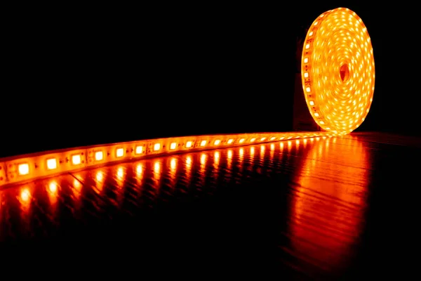 Cinta decorativa de diodo para iluminación, un rollo de tira led con luz cálida amarilla en el laminado del piso —  Fotos de Stock