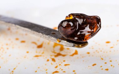 scraping high thc medical cannabis wax resin concentrate on white paper