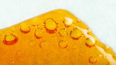 Kenevir reçinesi kağıtta akıyor, turuncu baloncuklar yüksek THC ile parlıyor.