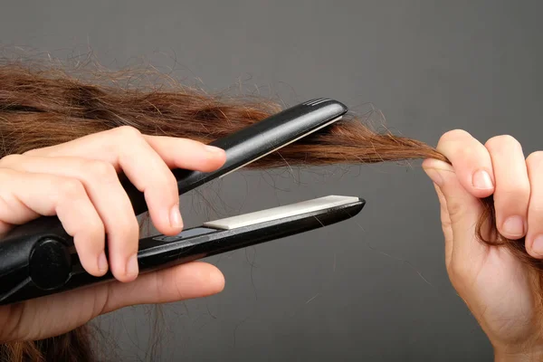 Stirare i capelli ricci con un ferro arricciacapelli, cura dei capelli. — Foto Stock