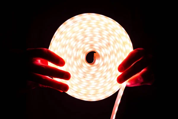 Luz de tira led, iluminación de diodo de bobina roja en la mano — Foto de Stock